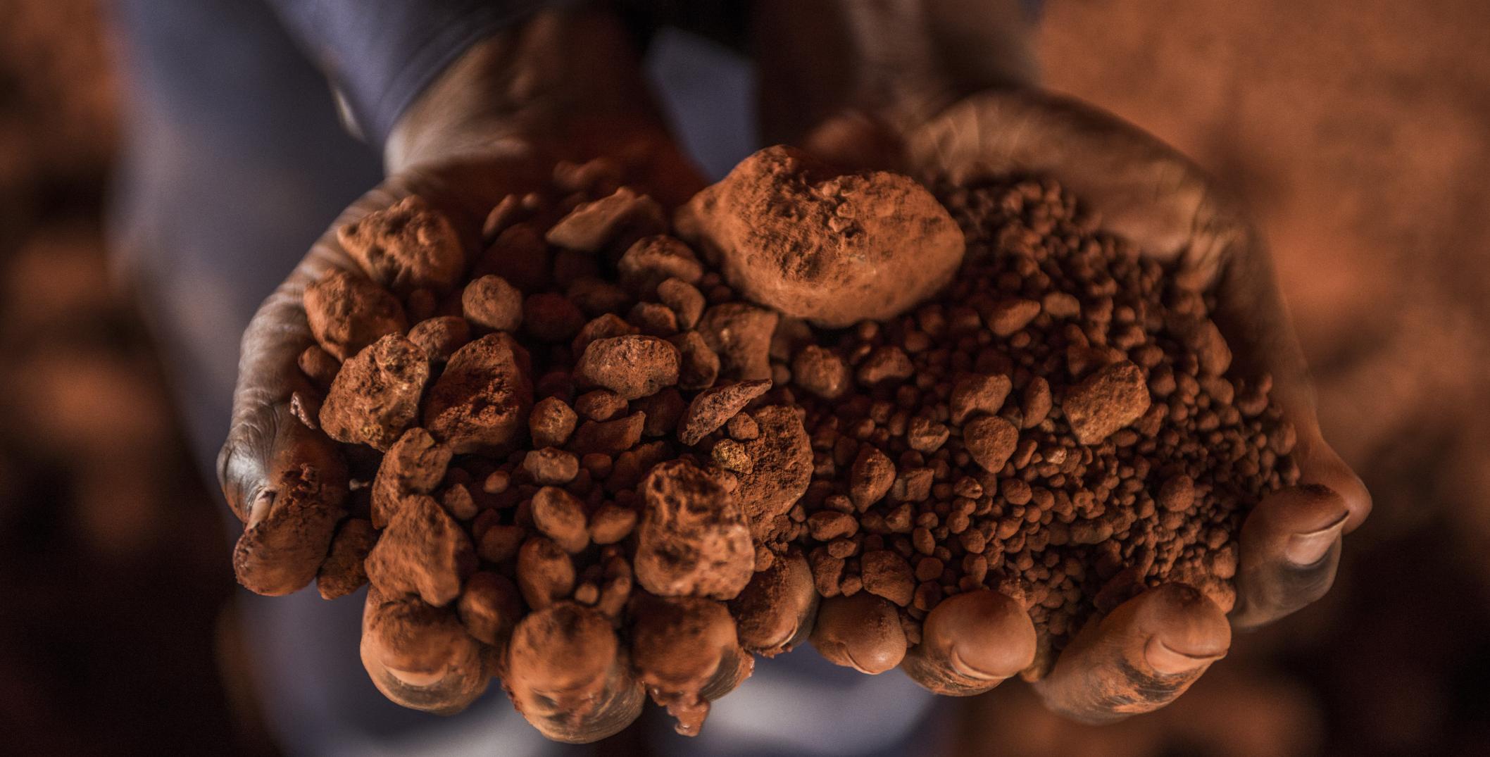 Hands holding bauxite in Guinea