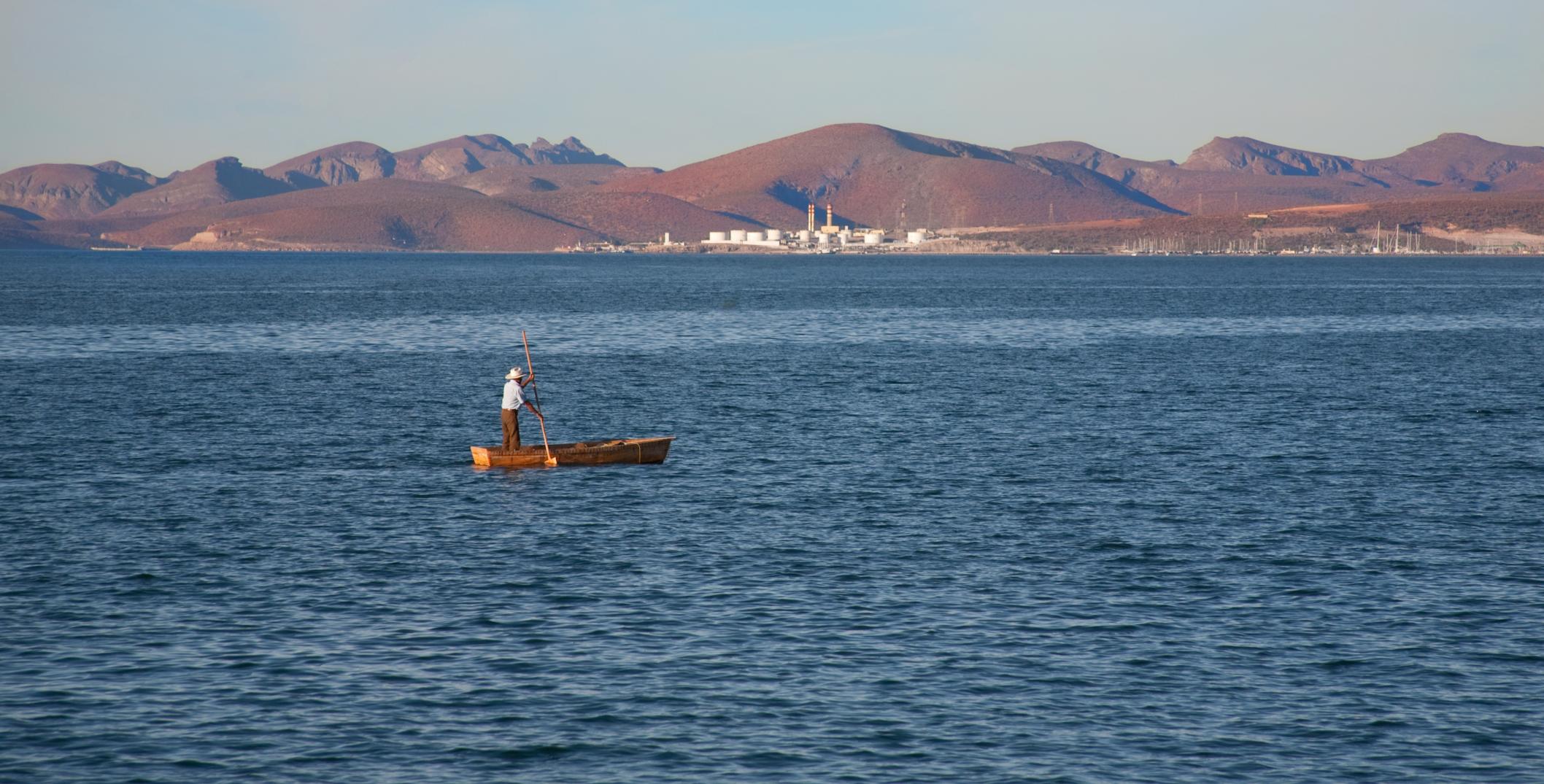 A man paddles small boat in Cortez sea, Mexico