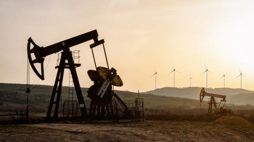 Oil pumps and wind turbines at sunset