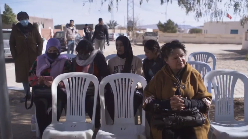 Women sitting on the chair with male youth in the background